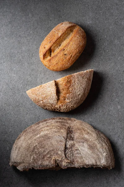 Tendido plano con mitades de pan en la superficie gris - foto de stock