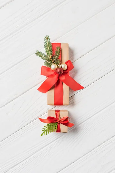Vista superior de dos cajas de regalo decoradas con adornos de Navidad y ramas de hoja perenne en la mesa de madera - foto de stock