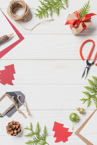 Flache Liege mit arrangiertem Weihnachtsgeschenk, Kugeln und immergrünen Zweigen auf Holztisch — Stockfoto