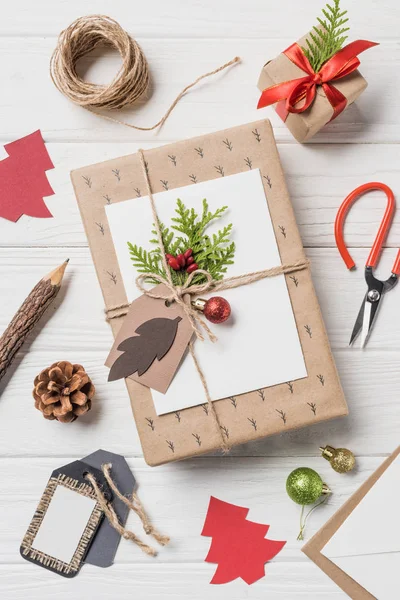 Vista superior de las cajas de regalo de Navidad arregladas, bolas y cono de hoja perenne en la mesa de madera - foto de stock