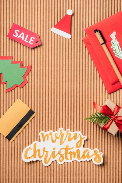 Top view of credit card, sale sign, decorated gift box and merry christmas lettering on surface — Stock Photo
