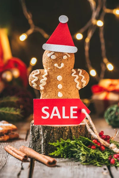 Weihnachten Lebkuchen Mann mit Weihnachtsmütze mit rotem Verkaufsschild auf Holzstumpf — Stockfoto