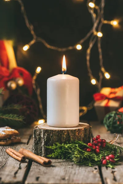 Vela de Navidad en tocón de madera con guirnalda ligera - foto de stock