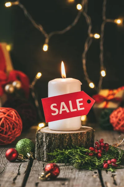 Christmas candle with red sale tag on wooden stump — Stock Photo
