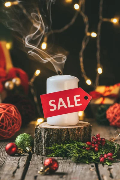 Christmas candle with red sale tag on wooden stump with decorations — Stock Photo