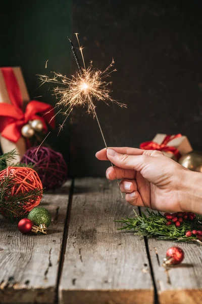 Cropped view of woman holding christmas sparkler — Stock Photo
