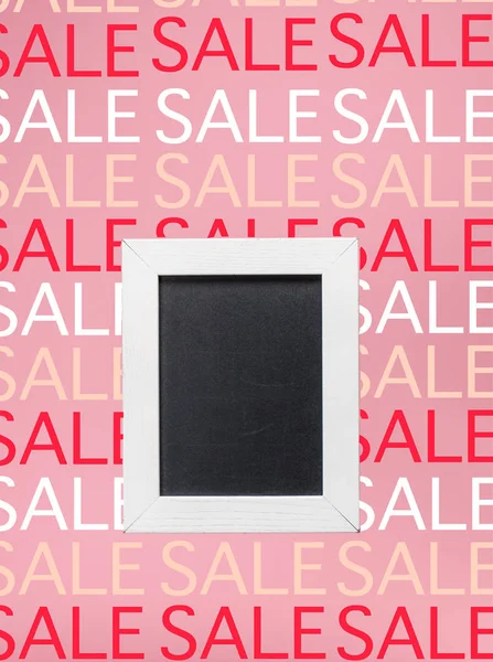 Empty blackboard in white frame on pink background with sale signs — Stock Photo