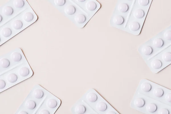 Vue du dessus des plaquettes thermoformées blanches avec des pilules sur plateau beige — Photo de stock