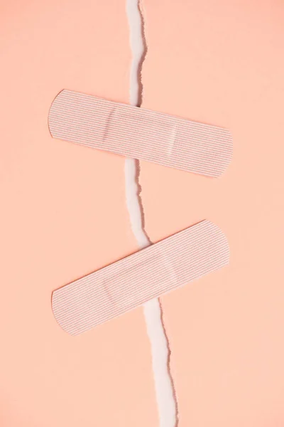 Top view of adhesive bandages holding two parts of torn paper — Stock Photo