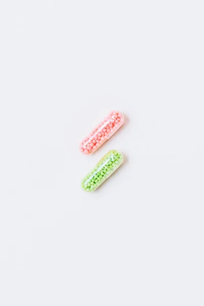 Top view of pink and green medical capsules on white — Stock Photo