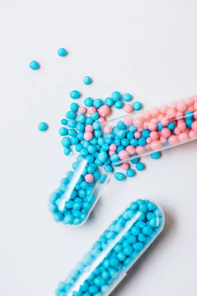 Close-up shot of broken blue and pink medical capsules on white surface — Stock Photo