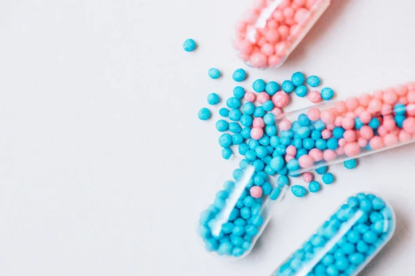Close-up de cápsulas médicas azuis e rosa quebradas em mesa branca — Fotografia de Stock