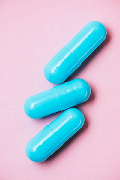 Primer plano de cápsulas médicas azules en rosa - foto de stock