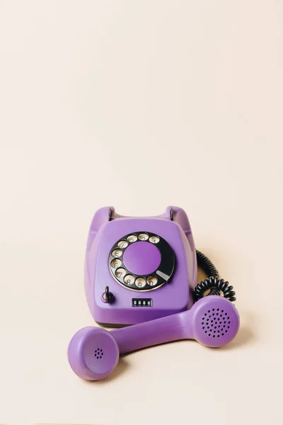 Violet vintage téléphone rotatif avec tube sur beige — Photo de stock