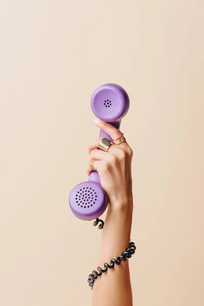 Partial view of woman holding purple phone tube on beige — Stock Photo