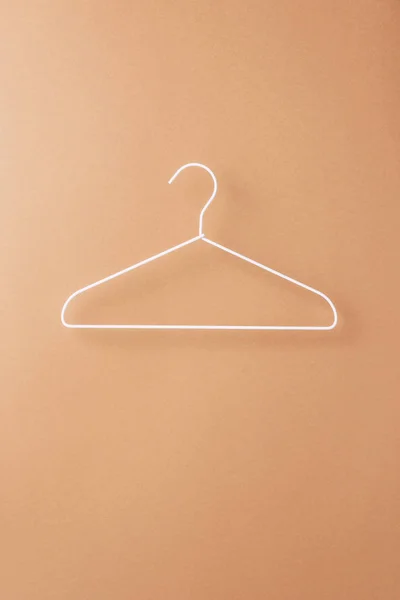 One empty white hanger on beige — Stock Photo