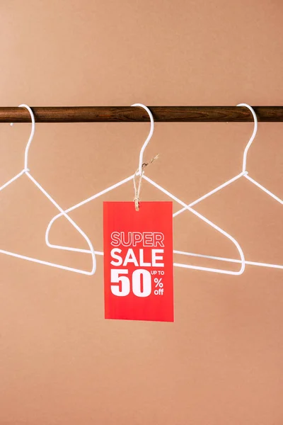 Hangers with red super sale tag - 50 percents discount for black friday shopping on beige — Stock Photo