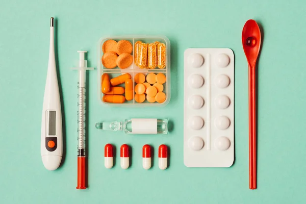 Top view of various medicines, syringe and thermometer on green — Stock Photo