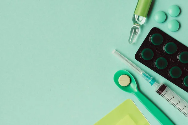 Draufsicht auf Ampulle mit Medikament, Blisterverpackung, Pillen und Spritze auf grünem Hintergrund — Stockfoto