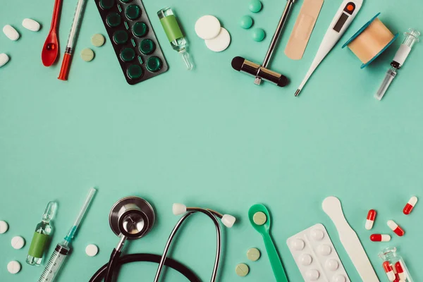 Colocação plana de várias pílulas médicas e instrumentos em fundo verde — Fotografia de Stock