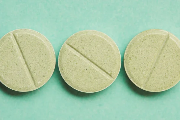 Вид сверху круглых таблеток на зеленый, крупный план — стоковое фото