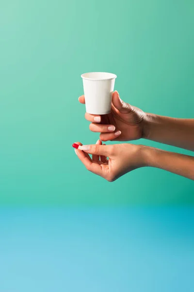 Cropped shot of person holding small cup and medical capsule isolated on green — Stock Photo