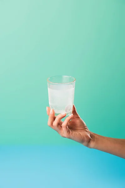 Tiro recortado de la persona que sostiene el vidrio con la medicina líquida aislada en verde - foto de stock