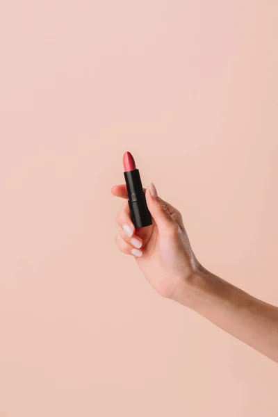 Cropped shot of woman holding lipstick isolated on beige — Stock Photo