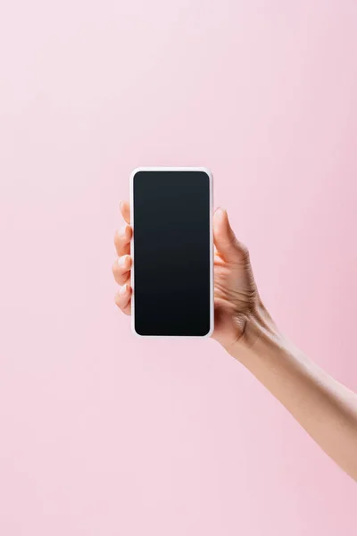 Обрізаний знімок жінки, що тримає смартфон з порожнім екраном ізольовано на рожевому — стокове фото