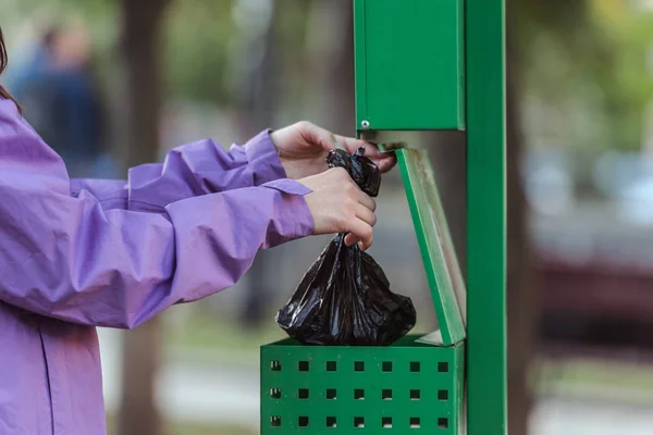 Plan recadré de femme mettant sac dans la poubelle dans le parc, nettoyage après concept animal — Photo de stock