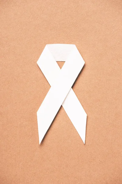 Elevated view of lung cancer awareness white ribbon on beige — Stock Photo