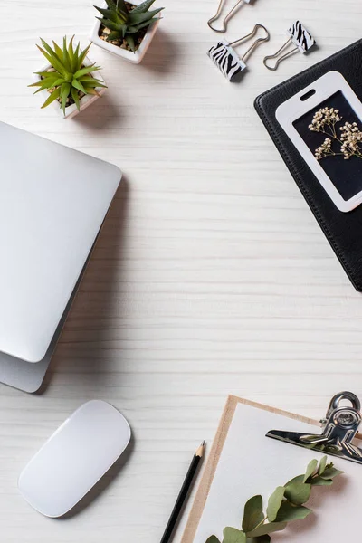 Flat lay with empty clipboard, computer mouse and laptop at table in office — Stock Photo