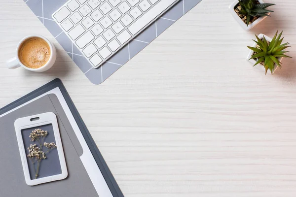 Plano con teclado de computadora, carpeta, macetas y taza de café en la mesa en la oficina - foto de stock