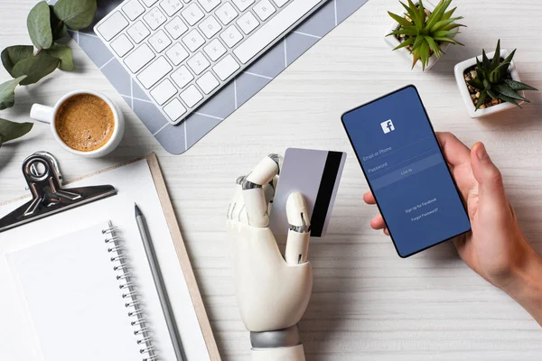 Teilansicht des Geschäftsmannes mit Prothesenarm, der Kreditkarte hält und Smartphone mit Eintrittskarten auf dem Bildschirm am Tisch im Büro benutzt — Stockfoto