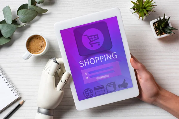 Cropped image of man with prosthesis hand using digital tablet with shopping on screen at table with coffee cup in office — Stock Photo