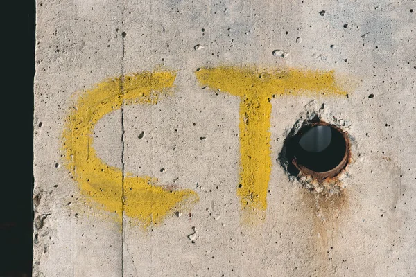 Yellow ct letters on white concrete wall — Stock Photo