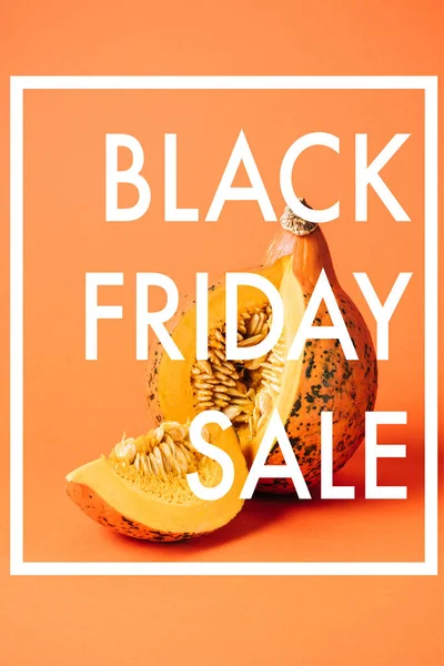 Vista da vicino della zucca cruda tagliata con iscrizione di vendita venerdì nero su sfondo arancione — Foto stock