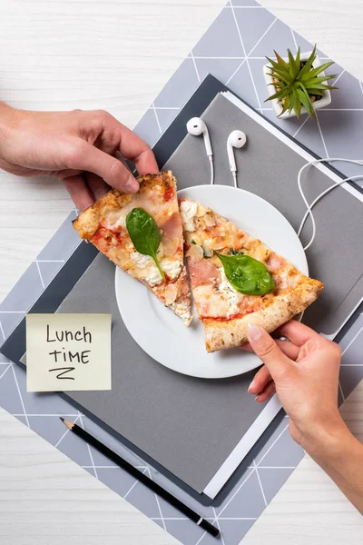 Vue partielle du dessus des personnes tenant des morceaux de pizza au-dessus de la plaque blanche au bureau — Photo de stock