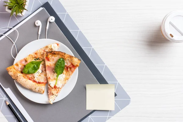 Vista superior de pizza, fones de ouvido e xícara de café descartável na mesa de madeira branca no escritório — Fotografia de Stock