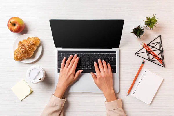 Tiro recortado de empresária usando laptop com tela em branco à mesa com café, maçã e croissant — Fotografia de Stock