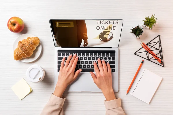 Foto recortada de la mujer de negocios utilizando el ordenador portátil con entradas sitio web en línea en la mesa con café, manzana y croissant - foto de stock