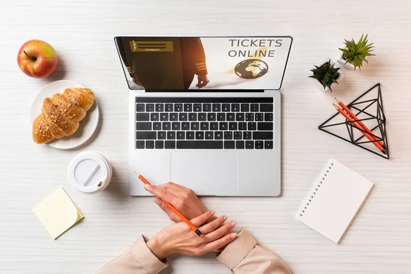 Cropped shot of female hands, laptop with tickets online website and lunch on table in office — Stock Photo