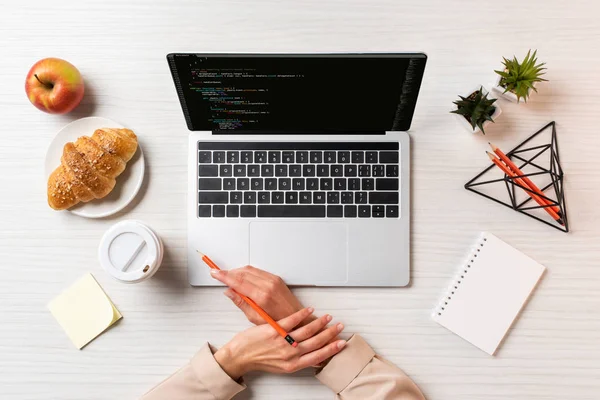 Plan recadré de mains féminines, ordinateur portable avec code html à l'écran et déjeuner sur la table au bureau — Photo de stock