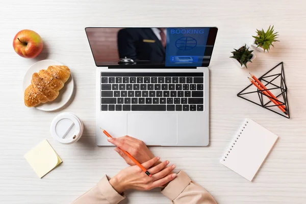 Cropped shot of female hands, laptop with booking website and lunch on table in office — Stock Photo