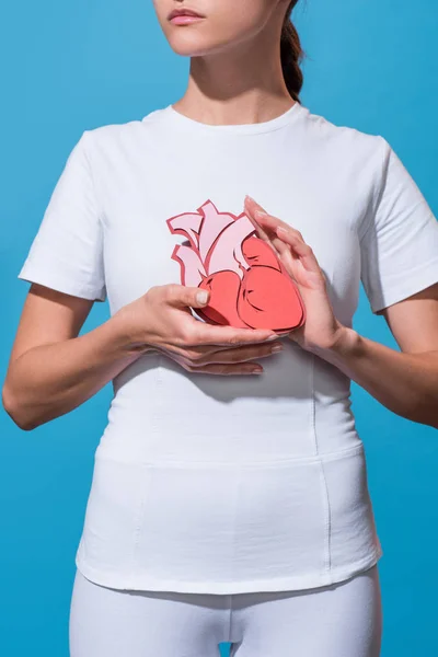 Cropped shot of woman in white tshirt holding paper made heart on blue backdrop — Stock Photo