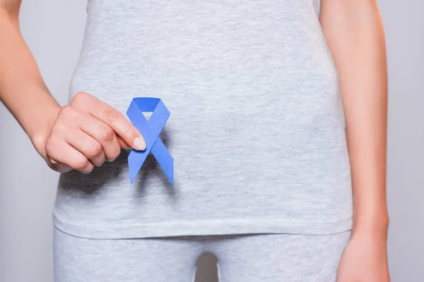 Частковий вигляд жінки, що тримає в руках обізнаність про рак простати синя стрічка на сірому тлі — стокове фото