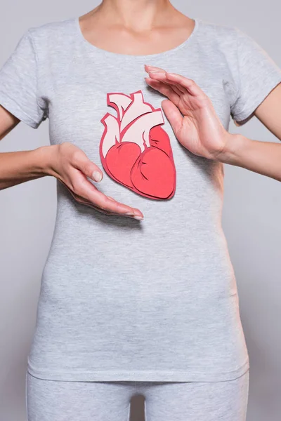 Partial view of woman with paper crafted heart on tshirt on grey backgroun — Stock Photo