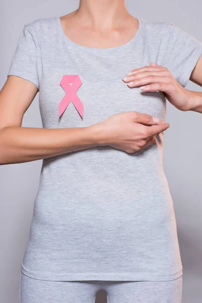 Tiro recortado de mulher com câncer de mama consciência fita rosa em fundo cinza — Fotografia de Stock