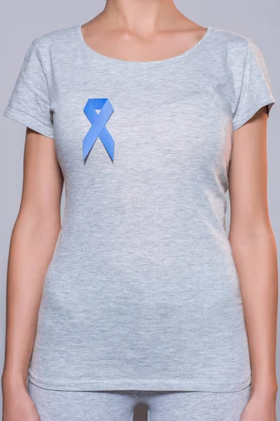 Cropped shot of woman in grey tshirt with prostate cancer awareness blue ribbon on grey backdrop — Stock Photo