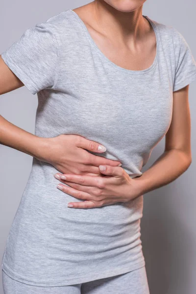 Частковий вид жінки, яка болить печінка на сірому фоні — стокове фото